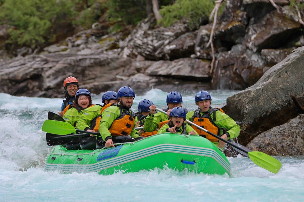 Family rafting adventure on turquoise river amid lush green forest, smiling and paddling.