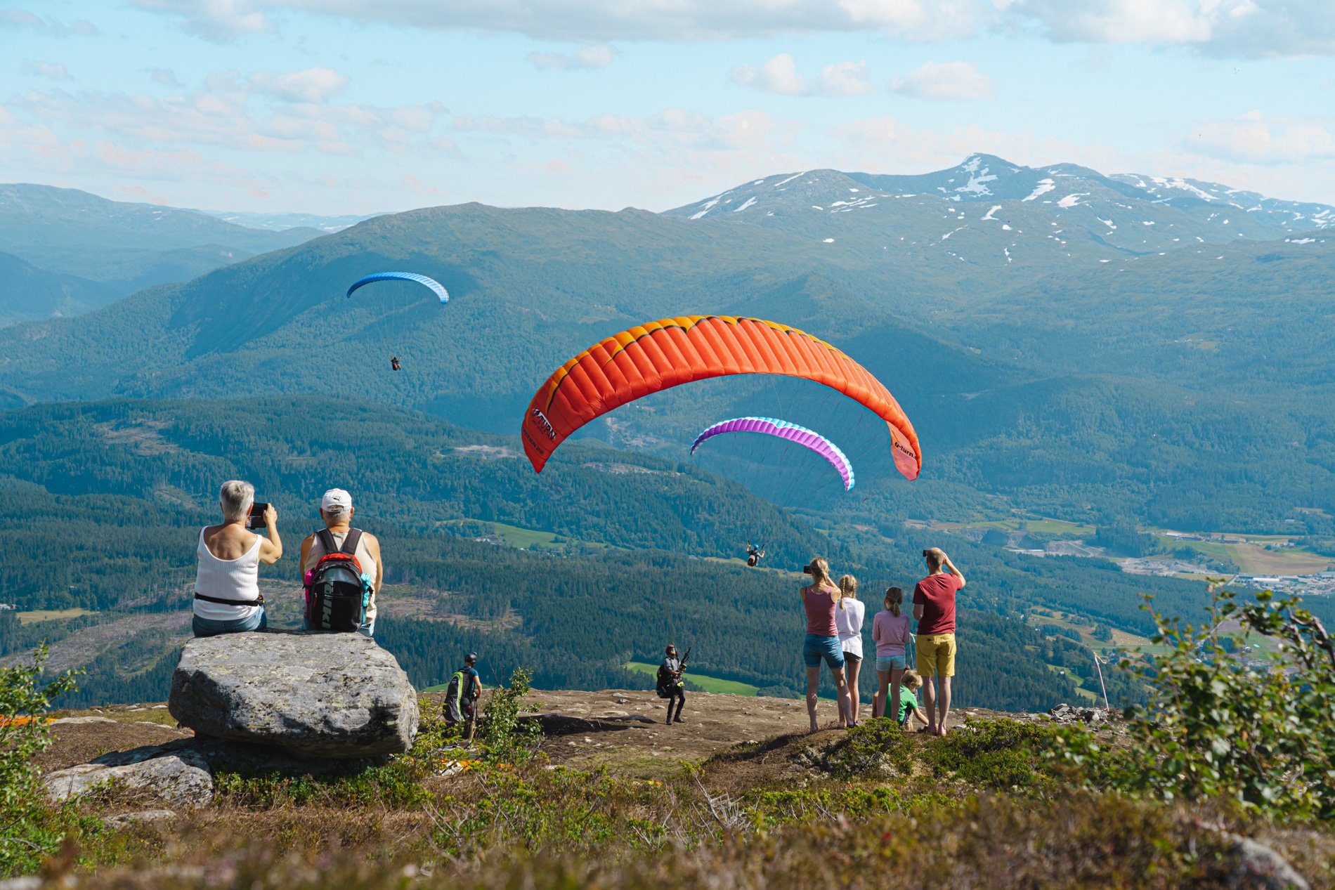 People watching paragliding from the top of Hangurstoppen in Voss, Norway