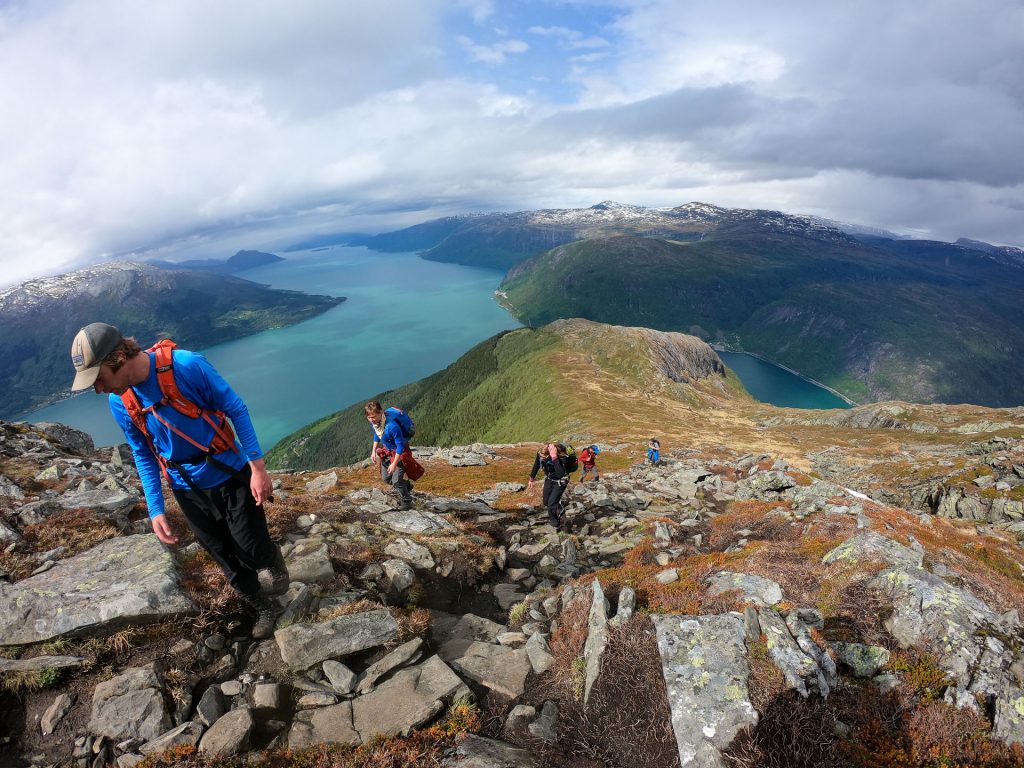 Hikers ascending Mount Oksen with a wide panoramic view of Hardangerfjord and Naeroyfjord