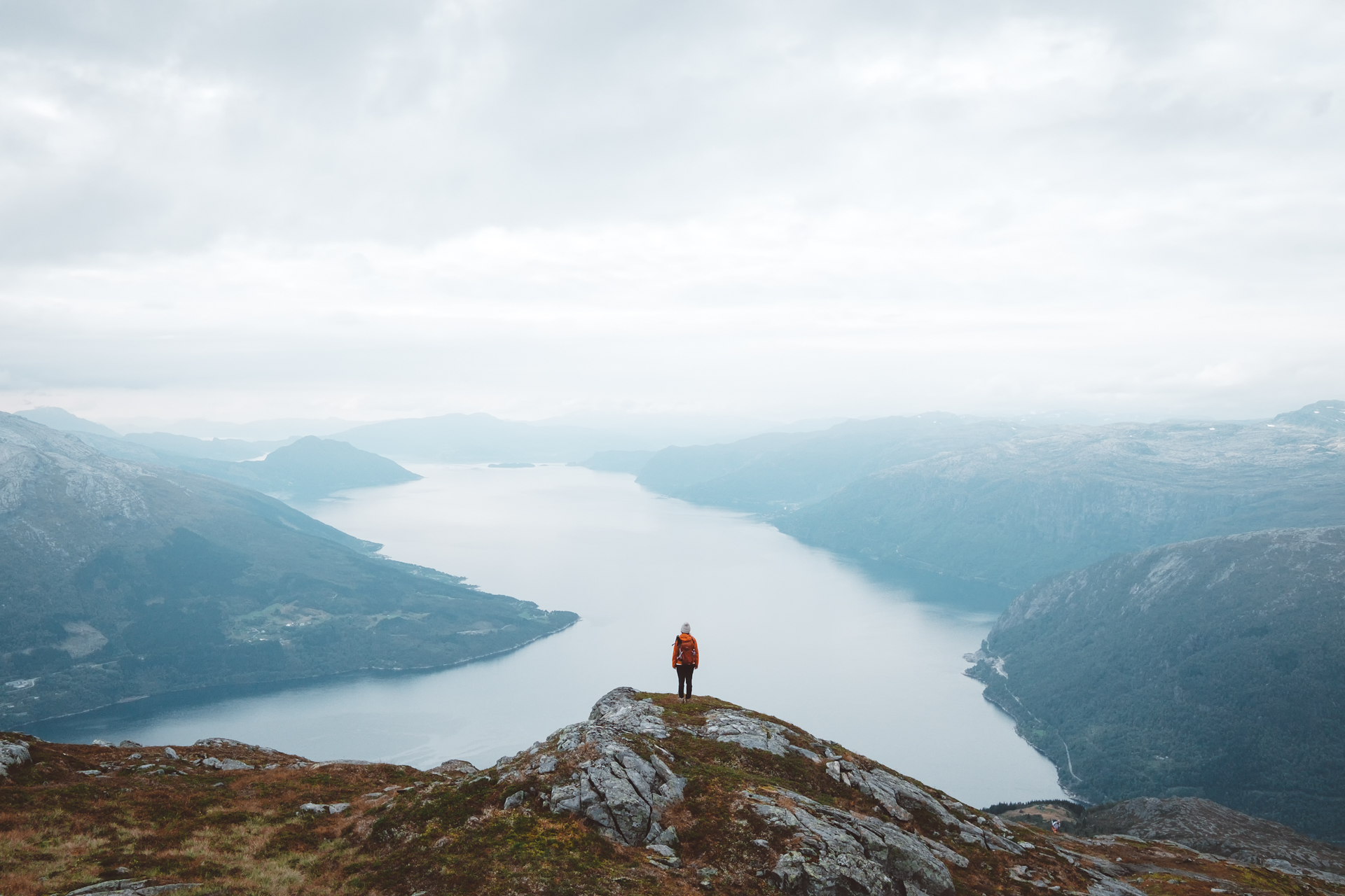 A woman standing on Hardangerfjord admiring the fjordland landscape that Norway is known for