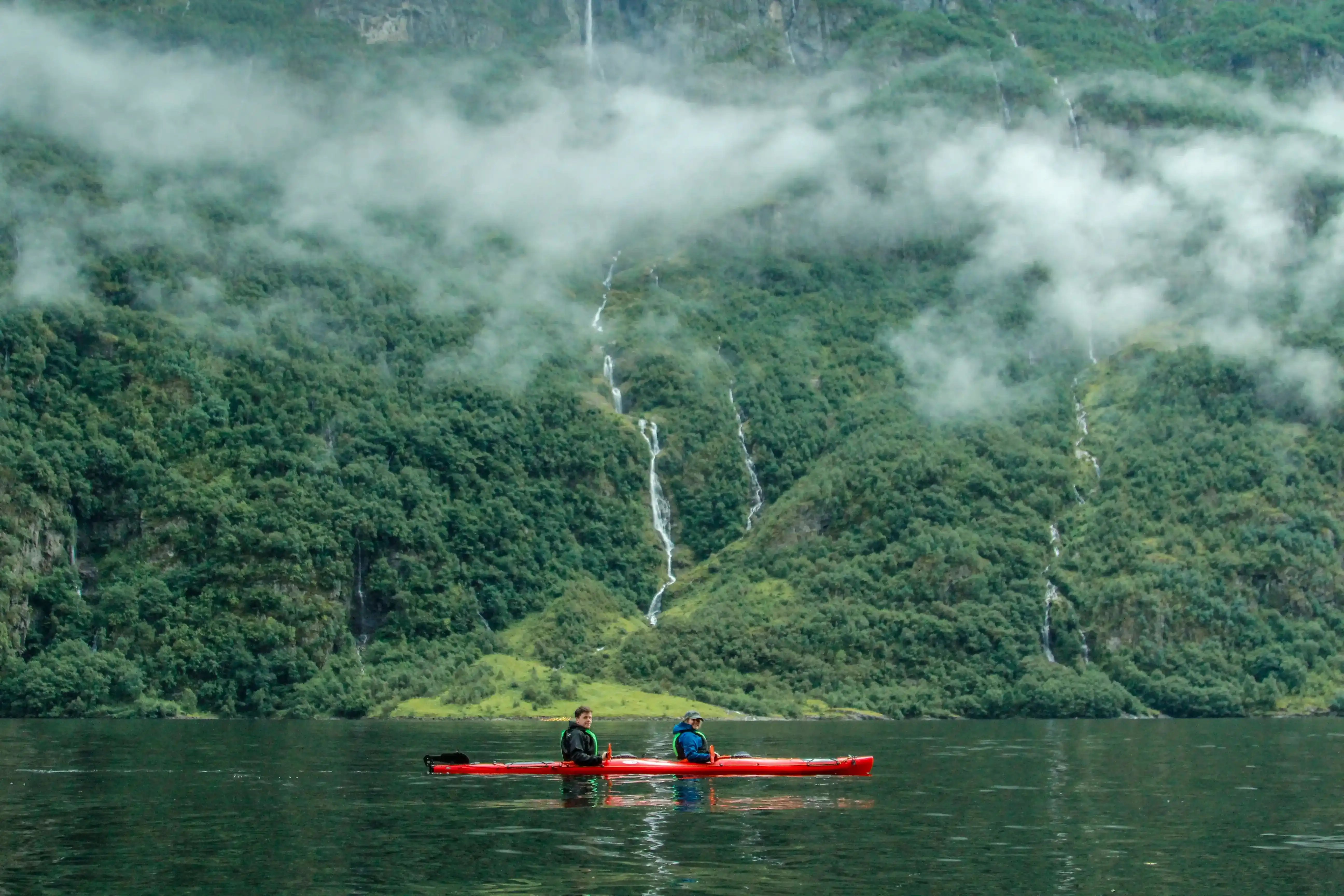 Two kayakers among the fjords in Fjord Norway near Voss on a guided multi-day Autumn tour