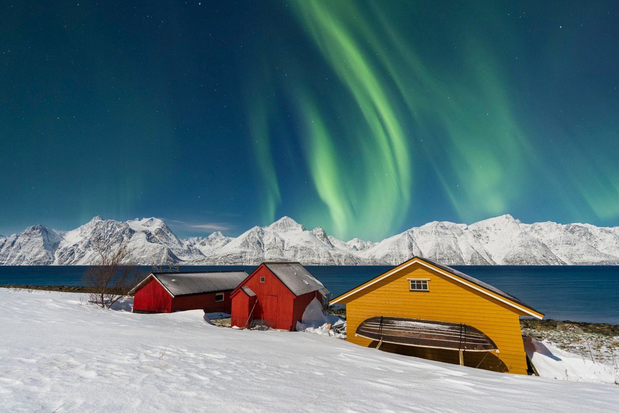 Classic Norwegian houses in Northern Norway with the Aurora Borealis shining in the distance