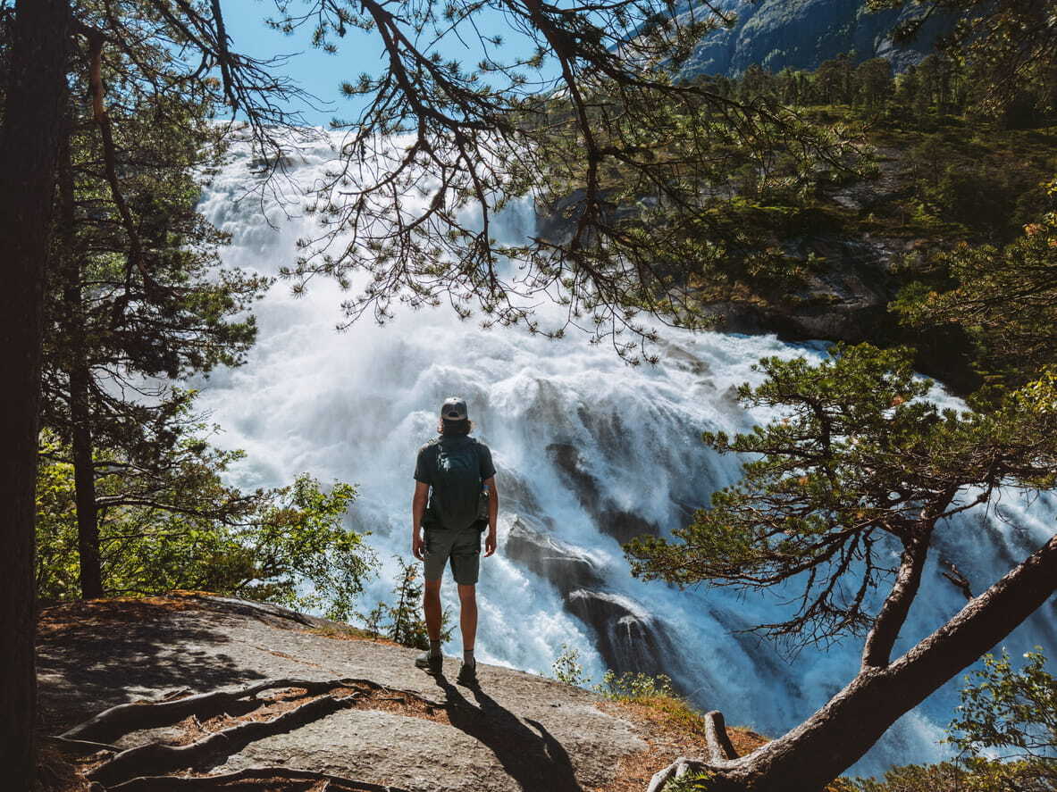 Hiker enjoying a view of Husedalen waterfall in Norway