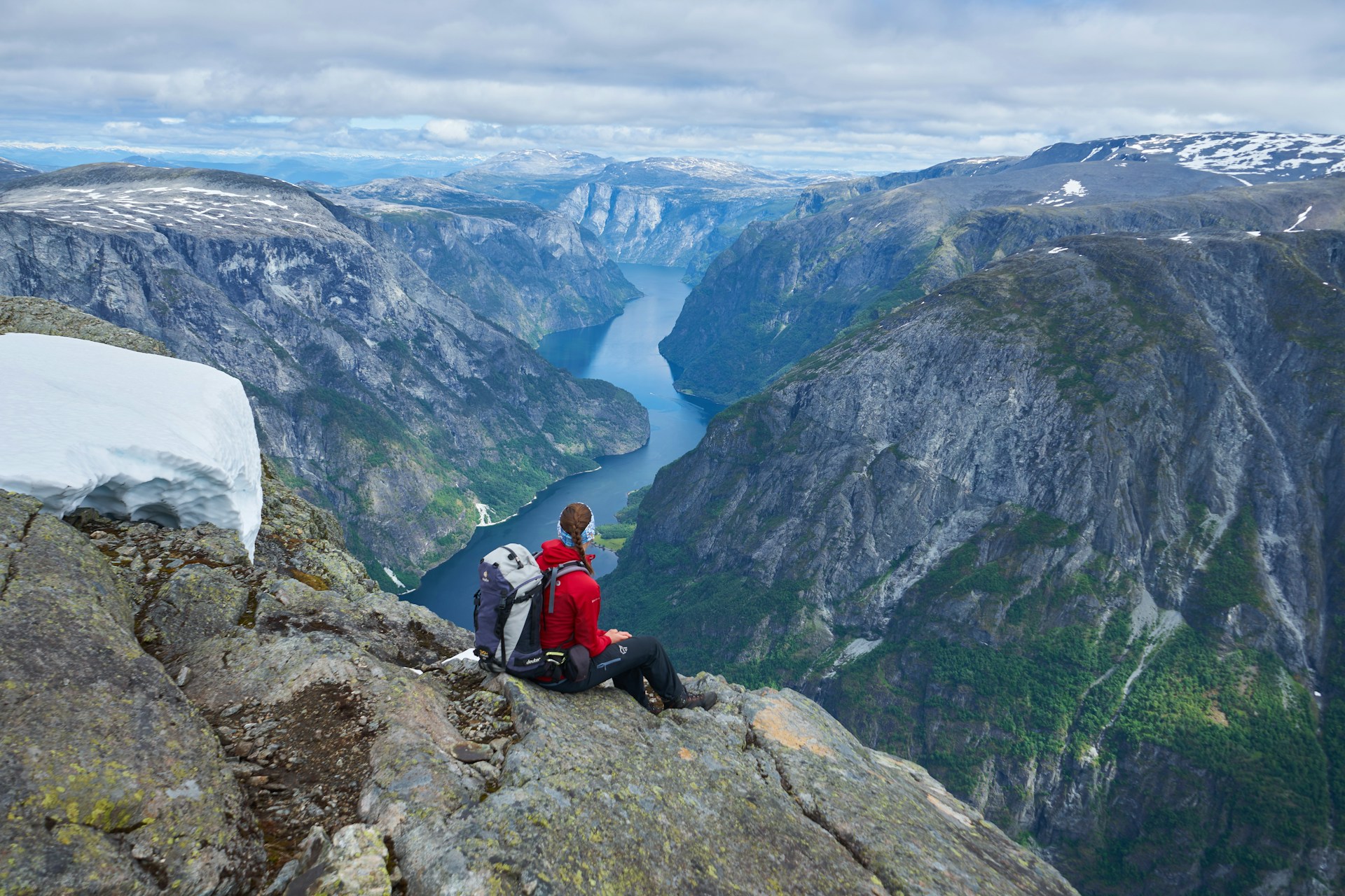 Hiker sitting atop of Naeroyfjord in Norway
