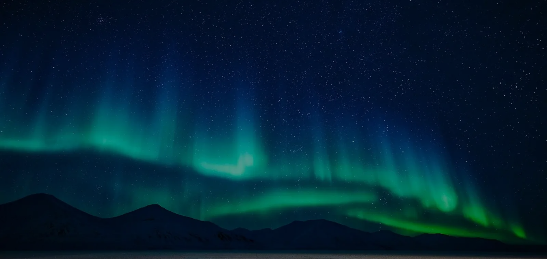 Aurora shining above a barren landscape in Svalbard, Norway