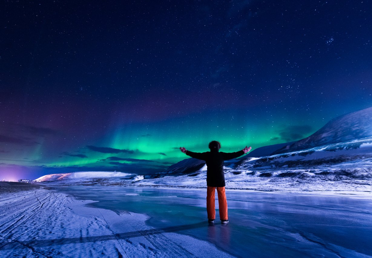 A man admiring the Northern Lights on the ice of Svalbard, Norway