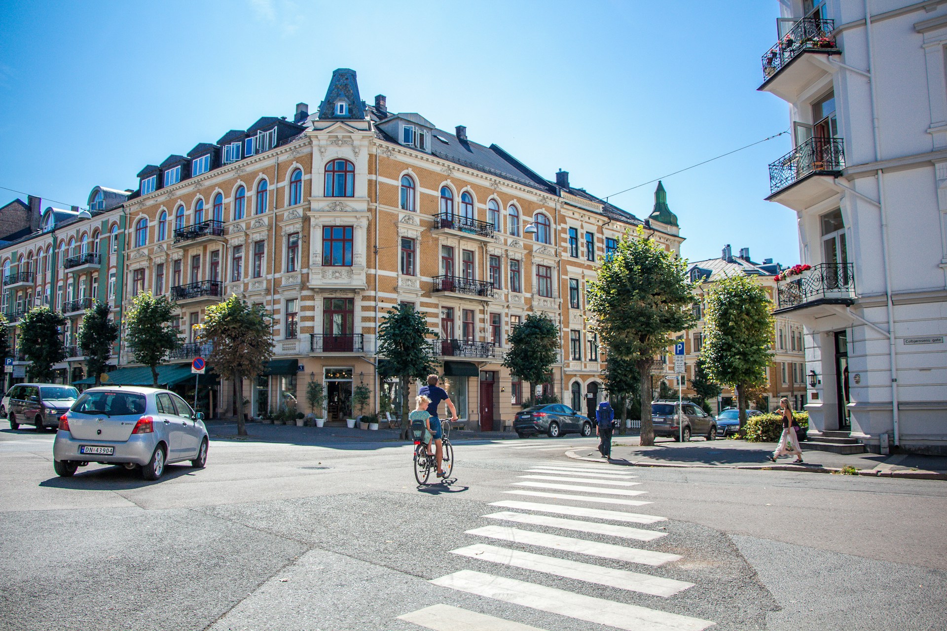 A man cycling with his child through an old street in Norway