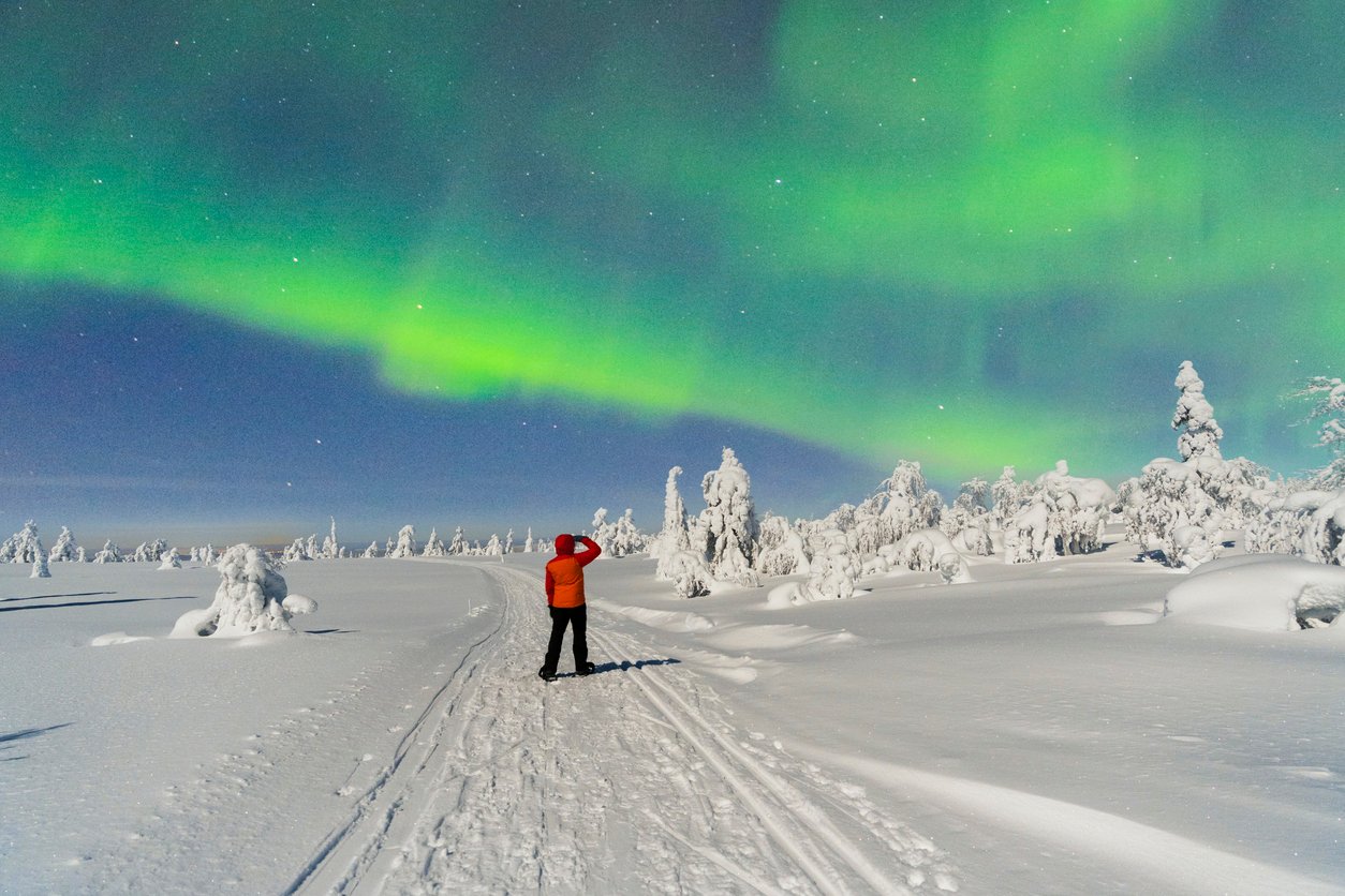 A man in Northern Norway hiking and admiring the Aurora Borealis on a trip during the day