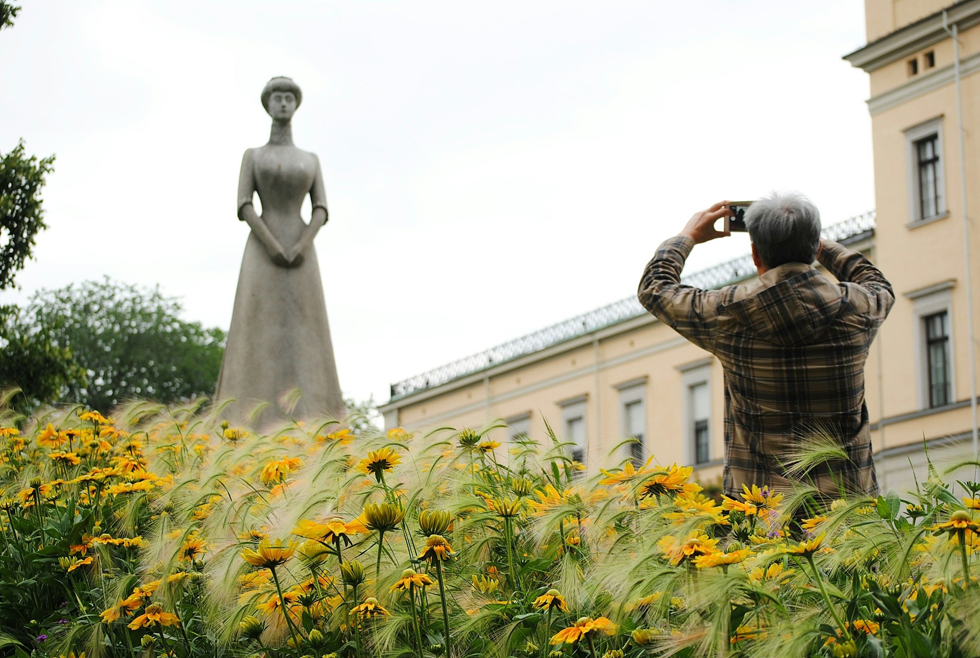 Man photographing a statue at the Royal Palace in Oslo
