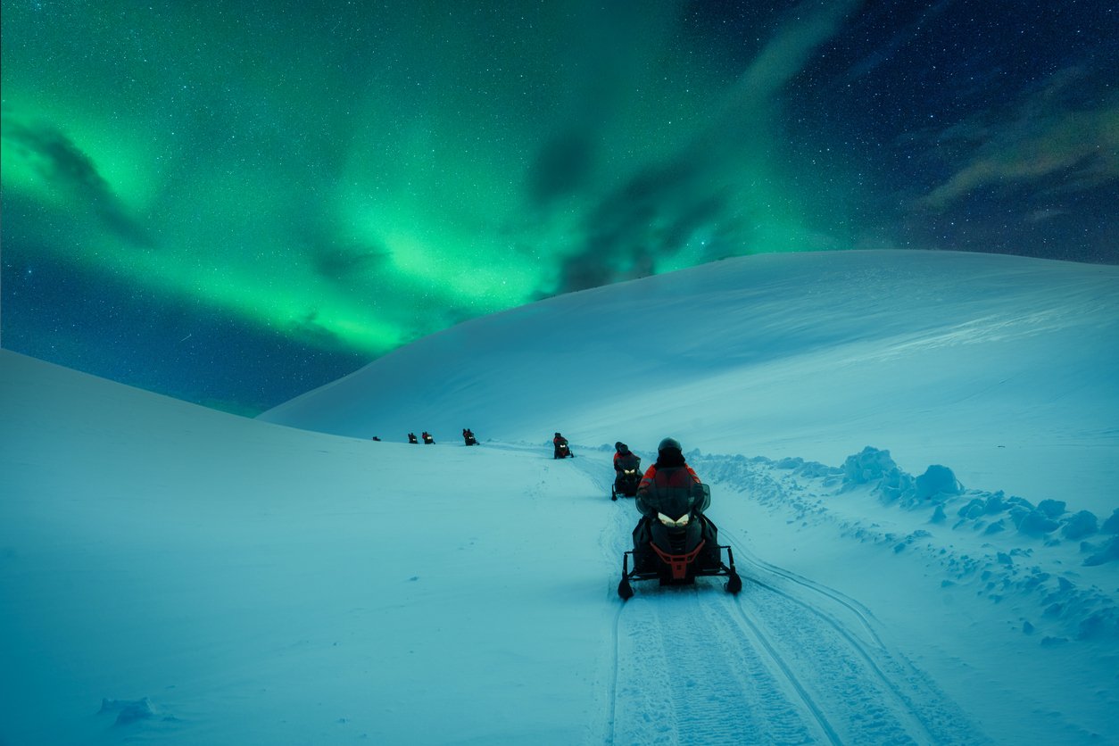 Men on a northern lights tour by Snowmobile