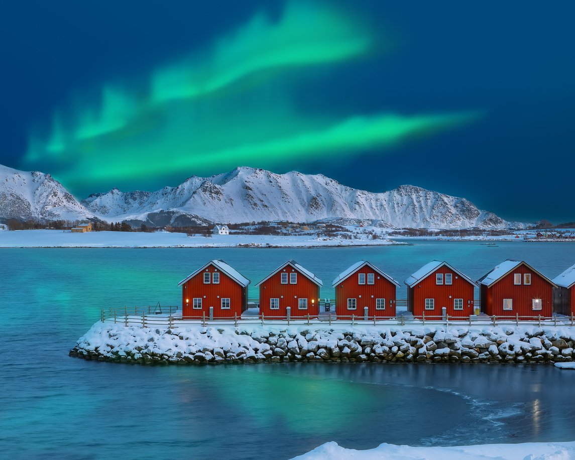 Wooden houses beneath the Northern Lights in Lofoten, Norway