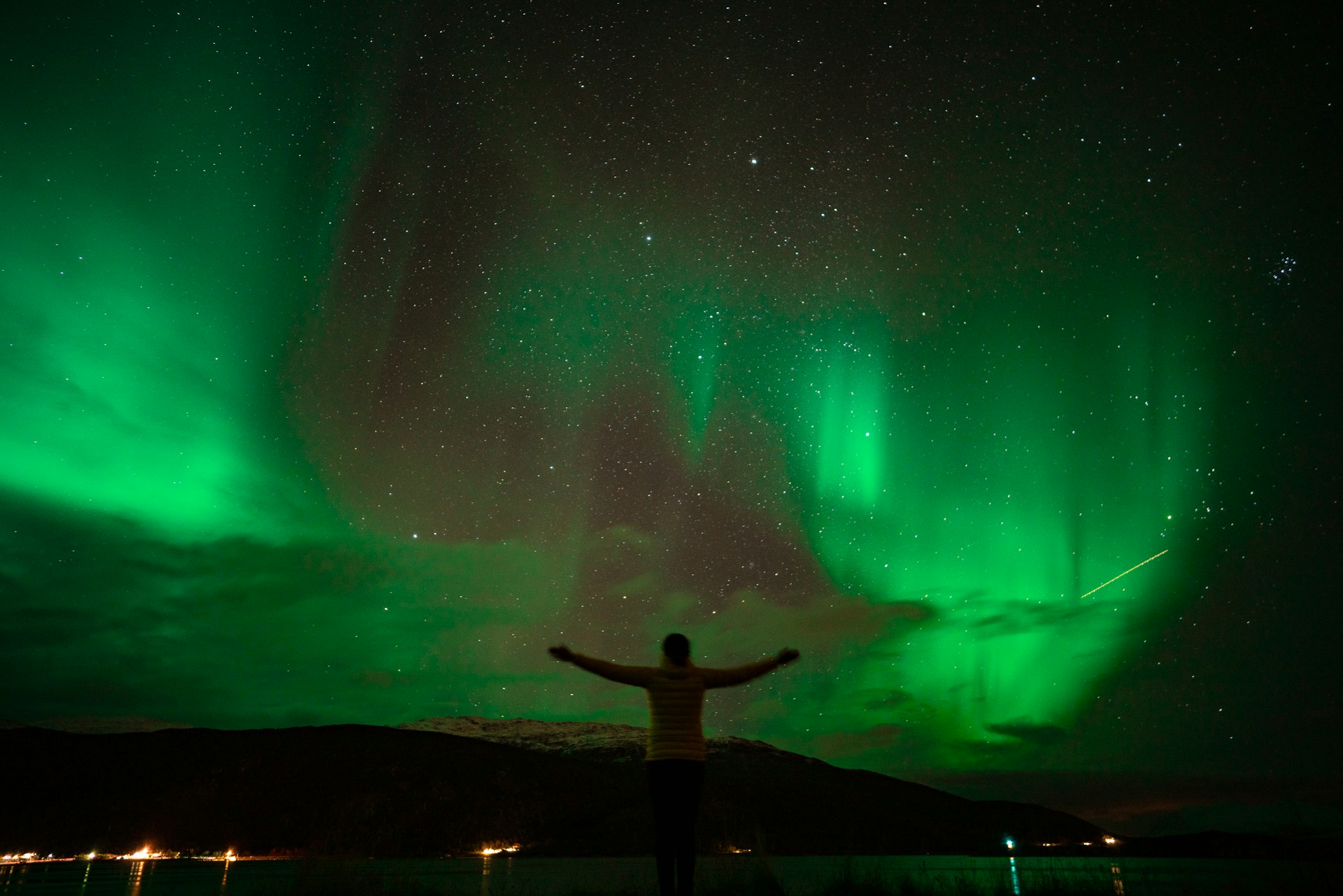 Triumphant man admiring the Northern Lights in Tromsø