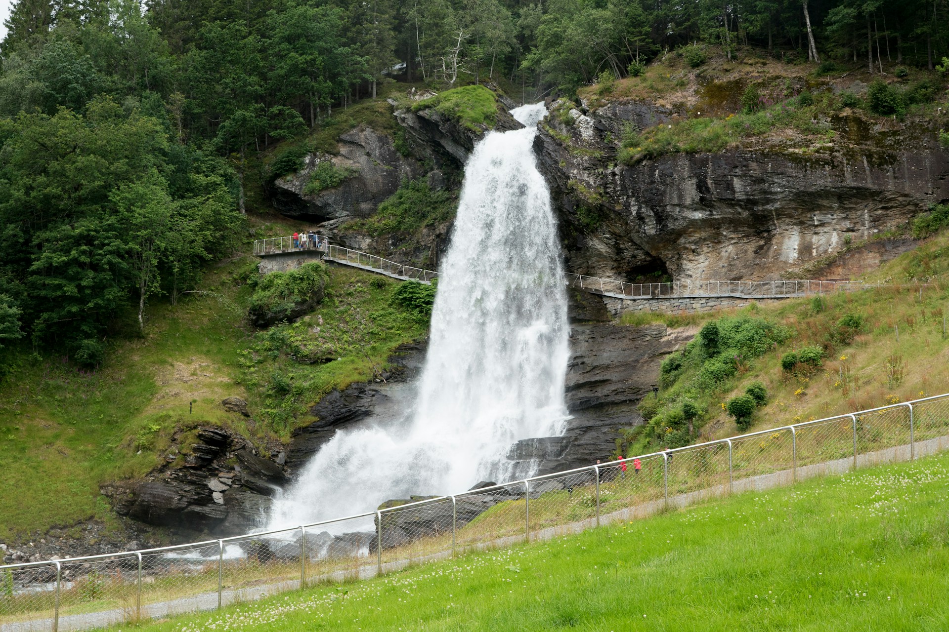 Tourists walking behind Steindalsfossen, Norway