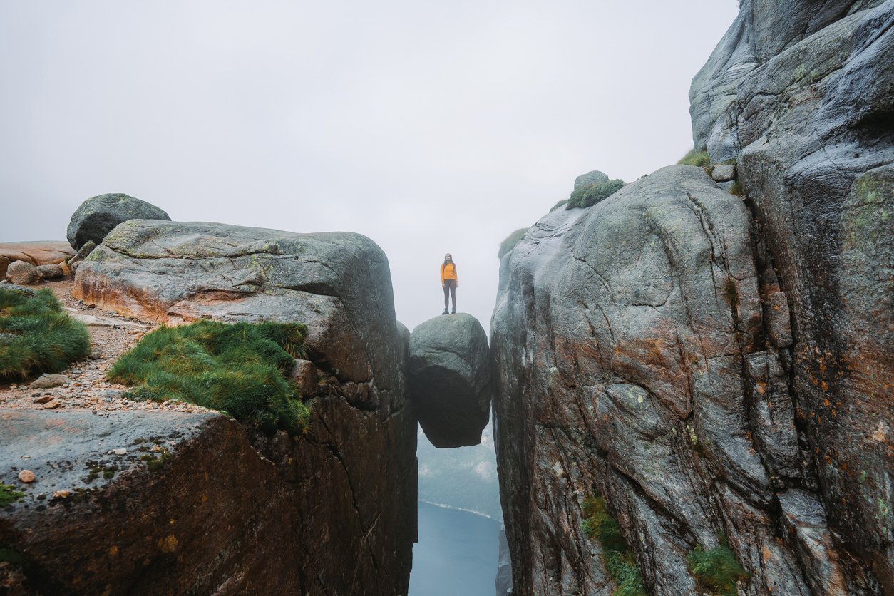 A woman standing atop of Kjeragbolten, Norway after a long hike